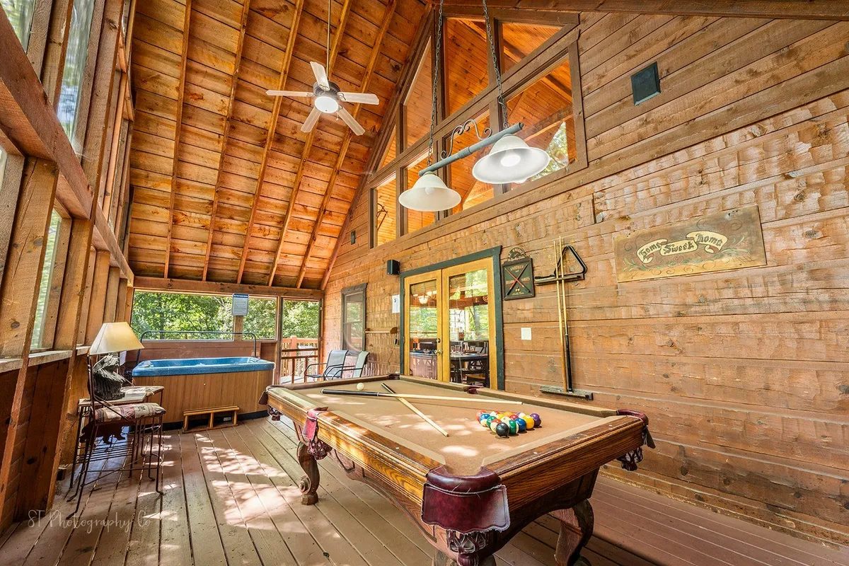 A lively interior scene featuring a pool table and hot tub with wooden beams and large windows letting in natural light. The atmosphere is recreational and relaxed, encouraging friendly competitions, celebrations, and unwinding together after a night out.