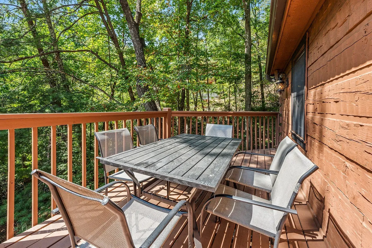 This image features an inviting outdoor seating area with a wooden table surrounded by trees. The tranquil environment suggests opportunities for stargazing, morning coffee, and unwinding together in nature.