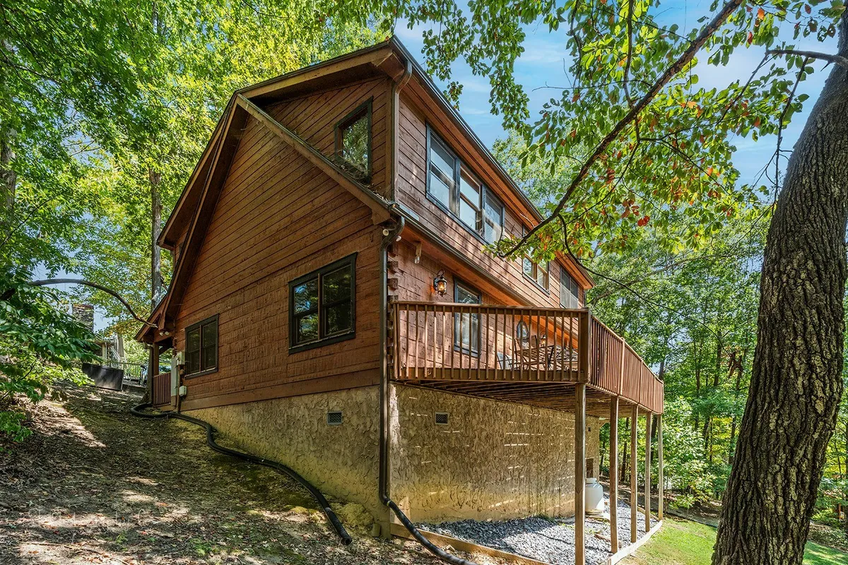 This exterior shot spotlights a wooden deck with large windows and a backdrop of serene natural surroundings. It suggests plenty of room for outdoor relaxation, group gatherings, and appreciation of the peaceful Smoky Mountain environment.